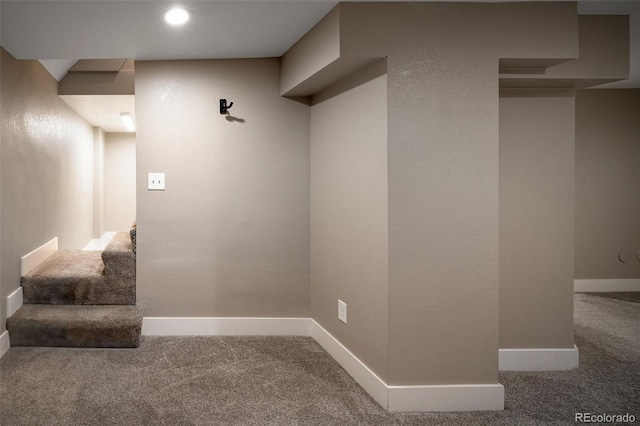 below grade area with baseboards, carpet floors, and a textured wall