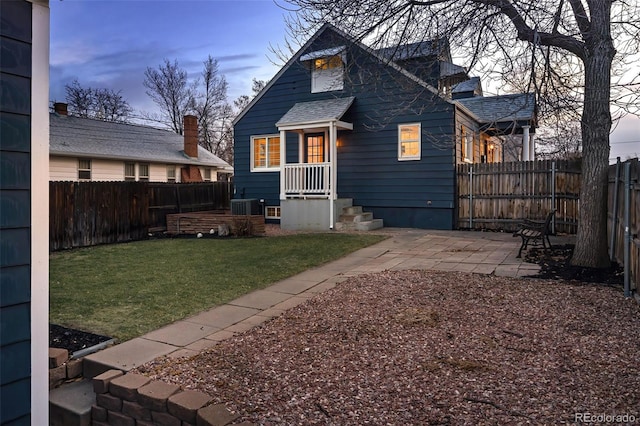 rear view of house featuring a patio area, a lawn, cooling unit, and a fenced backyard