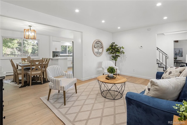 living room featuring baseboard heating, an inviting chandelier, and light hardwood / wood-style floors