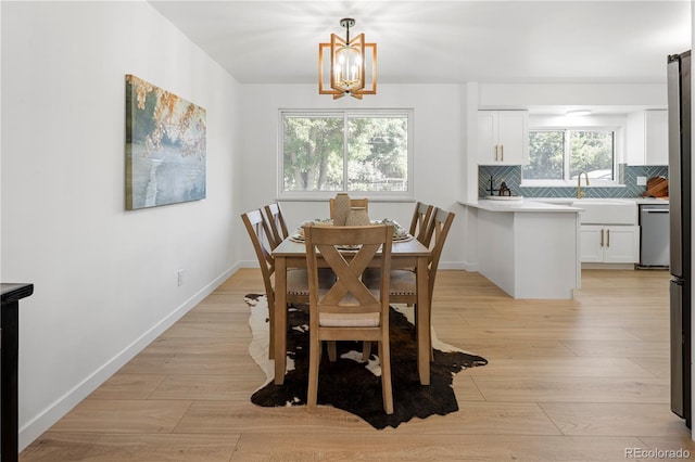 dining area with light hardwood / wood-style floors, plenty of natural light, sink, and an inviting chandelier