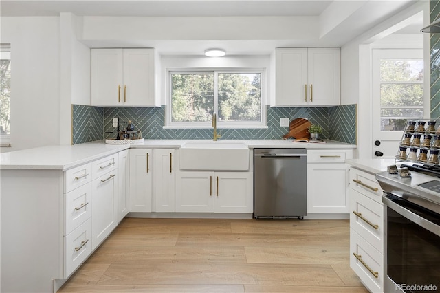 kitchen featuring white cabinets, light hardwood / wood-style floors, kitchen peninsula, and appliances with stainless steel finishes