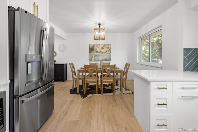 dining area with light wood-type flooring and a notable chandelier