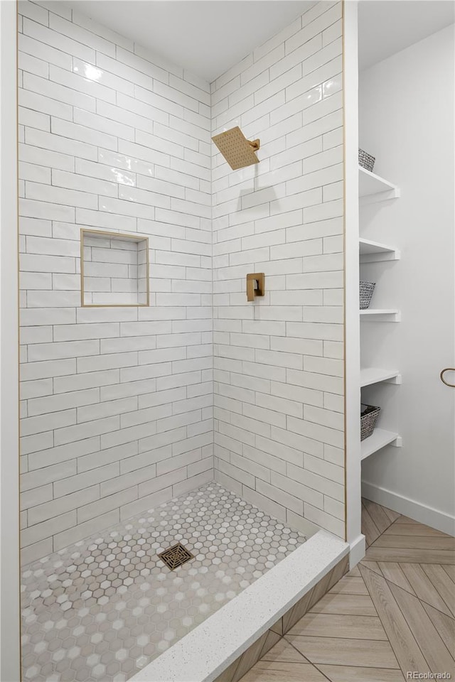 bathroom featuring a tile shower and parquet floors