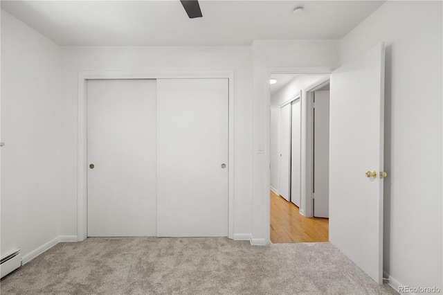 unfurnished bedroom with a closet, ceiling fan, light colored carpet, and a baseboard radiator