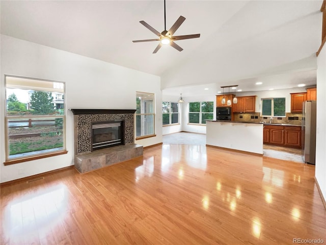 584 W Prestwick Way, Castle Rock, CO 80104 - unfurnished living room with a sink, light wood finished floors, a tile fireplace, a ceiling fan, and baseboards