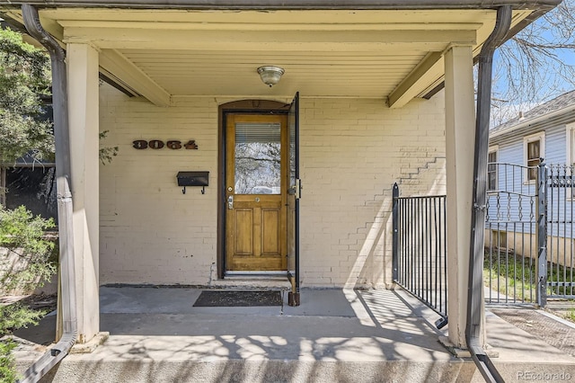 view of exterior entry with fence and brick siding