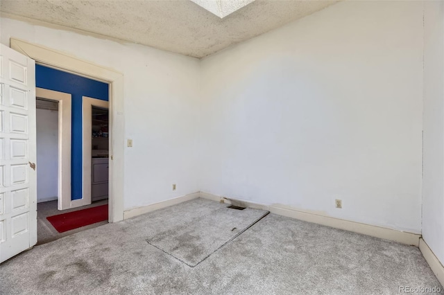 carpeted empty room featuring washer / dryer, baseboards, and a textured ceiling