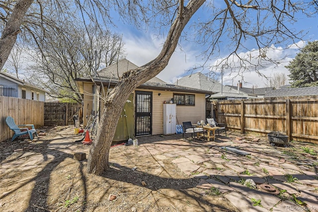 back of property featuring a fenced backyard, a patio area, a fire pit, and a shingled roof