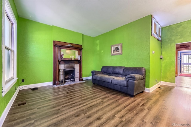 living area with a textured wall, visible vents, wood finished floors, and a tile fireplace