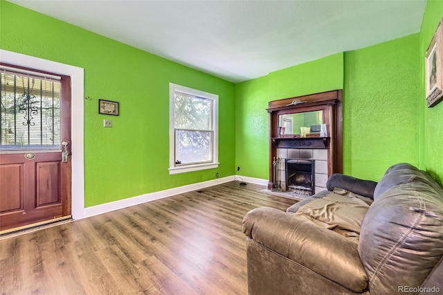 living area featuring baseboards, a textured wall, wood finished floors, and a fireplace