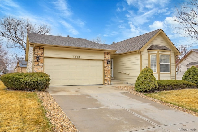 ranch-style house with concrete driveway, stone siding, roof with shingles, an attached garage, and a front yard