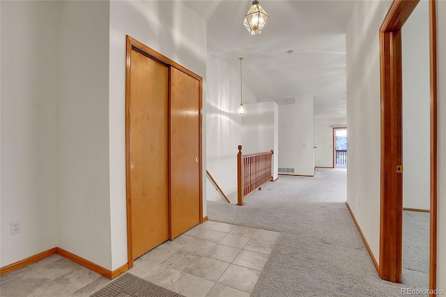 hall featuring baseboards, visible vents, light colored carpet, and an upstairs landing