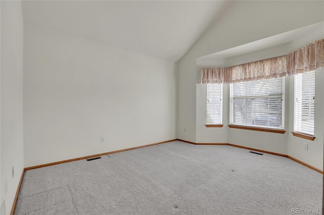 unfurnished room featuring vaulted ceiling, carpet flooring, and baseboards