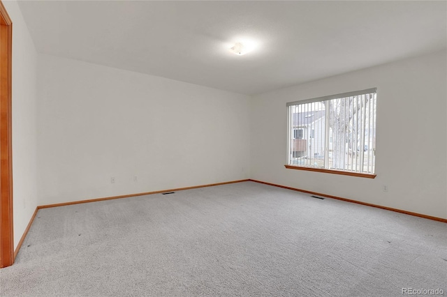 carpeted empty room featuring visible vents and baseboards