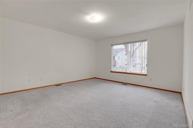 spare room with carpet flooring, visible vents, and baseboards