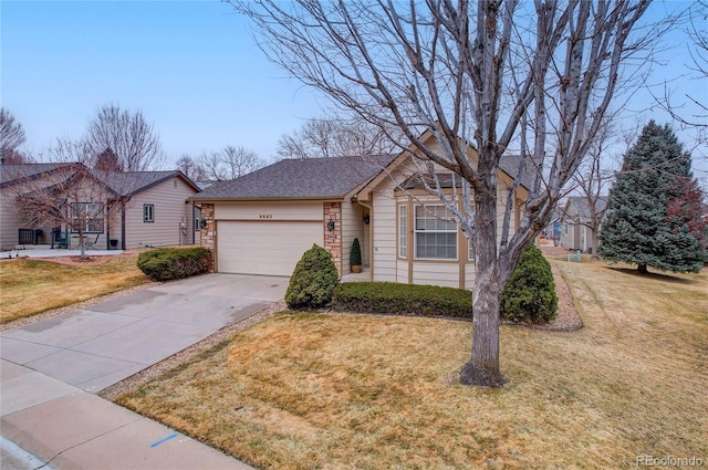 ranch-style house with a garage, a shingled roof, concrete driveway, and a front yard