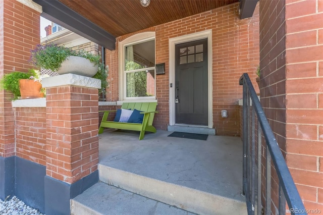 doorway to property with covered porch and brick siding