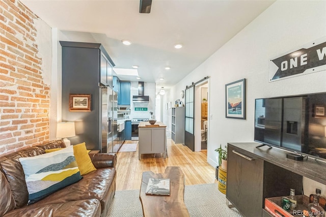 living area with recessed lighting, light wood-style flooring, brick wall, and a barn door