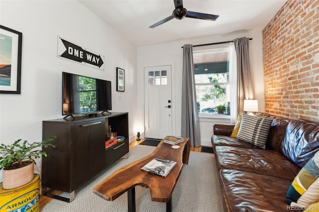 living room with brick wall, baseboards, ceiling fan, and wood finished floors