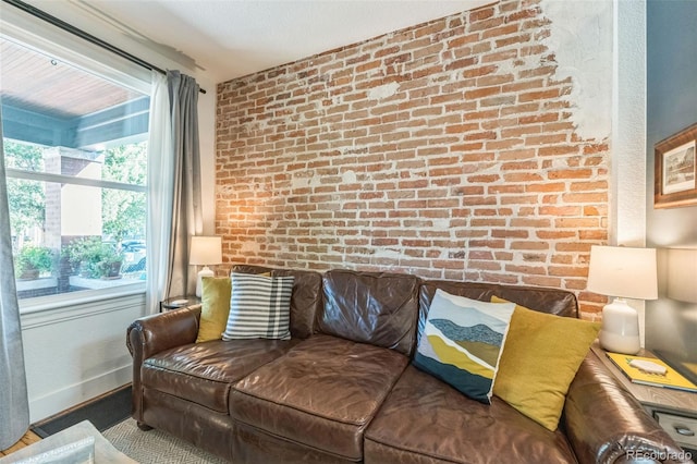 living area featuring brick wall and baseboards