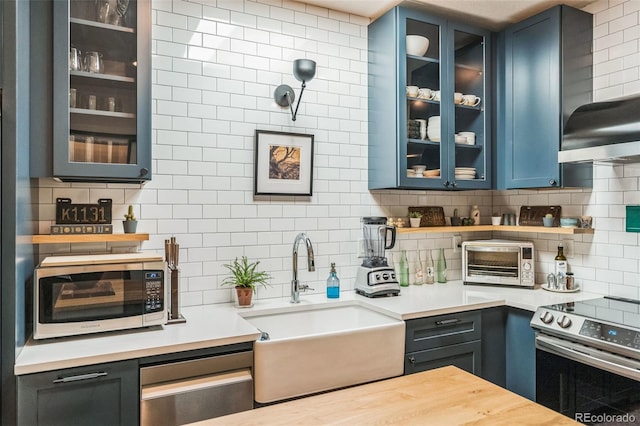 kitchen featuring a toaster, appliances with stainless steel finishes, light countertops, and a sink