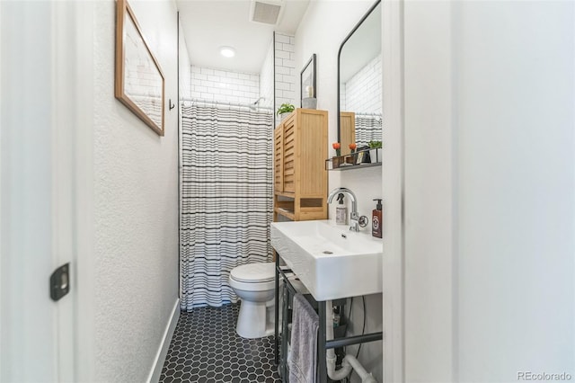 bathroom featuring baseboards, visible vents, a shower with shower curtain, toilet, and a sink