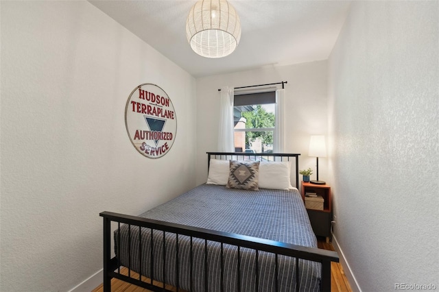 bedroom with a textured wall, baseboards, and wood finished floors