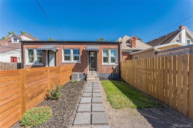 rear view of property featuring entry steps, brick siding, fence, and central air condition unit