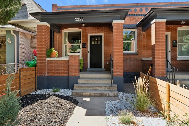 entrance to property with brick siding and fence