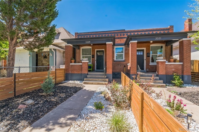 3329 N High St, Denver, CO 80205 - view of front of house featuring a chimney, brick siding, covered porch, and fence private yard