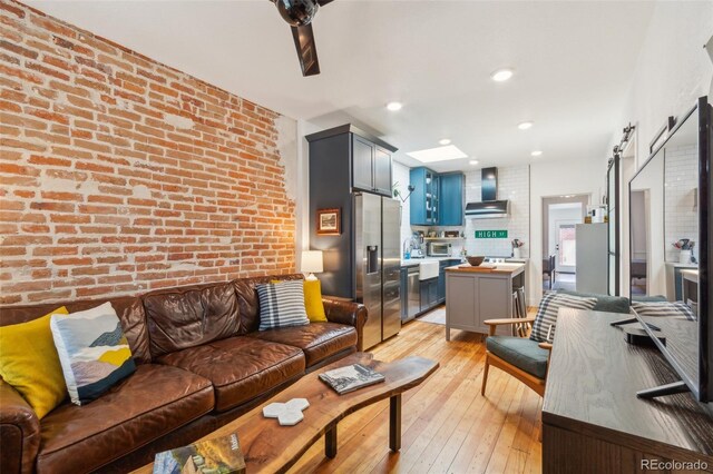3329 N High St, Denver, CO 80205 - living area with a barn door, light wood-style flooring, and brick wall