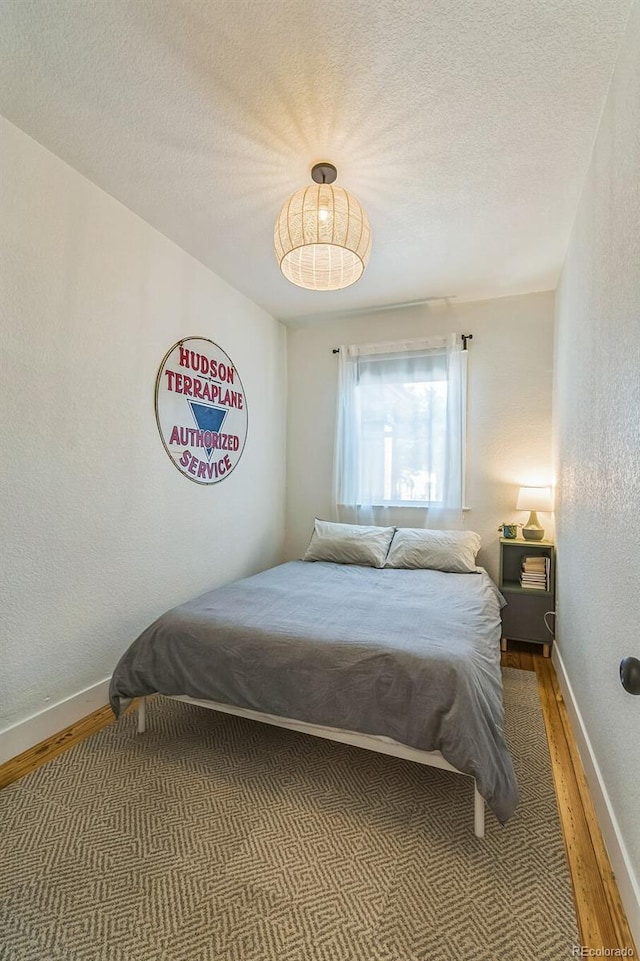 3329 N High St, Denver, CO 80205 - bedroom with a textured ceiling, a textured wall, baseboards, and wood finished floors