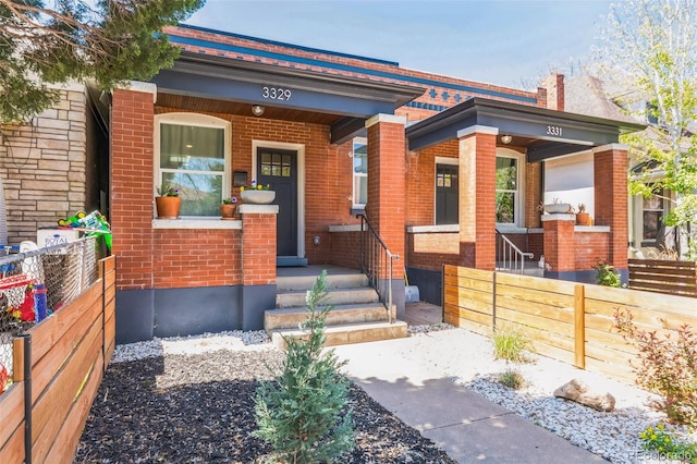 3329 N High St, Denver, CO 80205 - view of front facade with a porch, brick siding, and fence