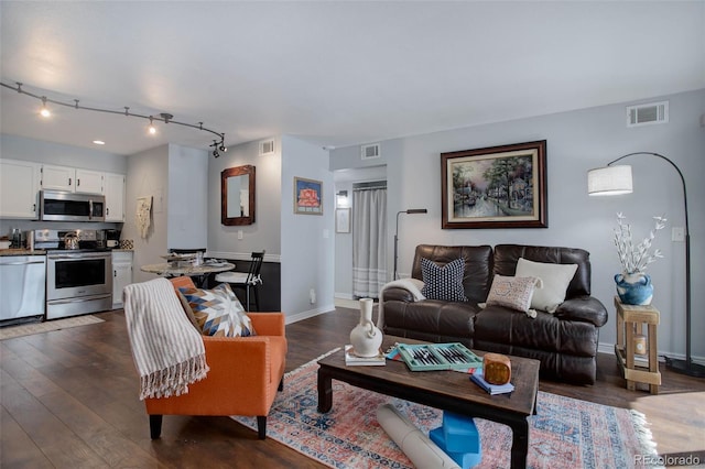 living room with dark wood-type flooring and track lighting