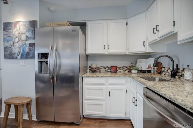 kitchen with white cabinetry, appliances with stainless steel finishes, light stone countertops, and sink