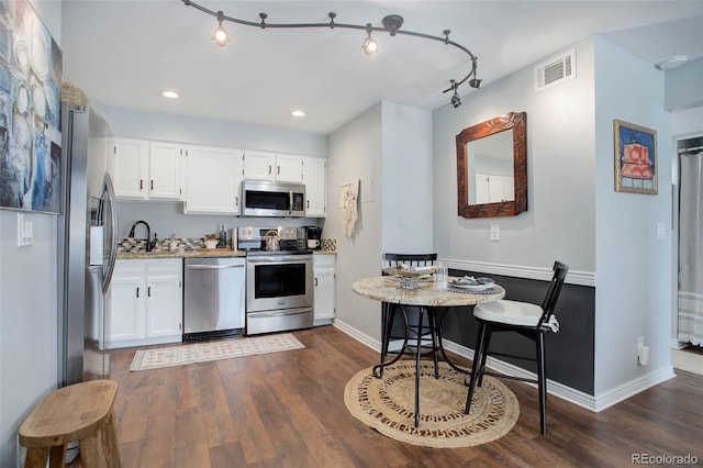 kitchen featuring white cabinetry, track lighting, stainless steel appliances, and dark hardwood / wood-style floors