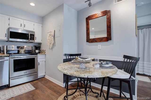 kitchen featuring stainless steel appliances, white cabinetry, light stone countertops, and dark hardwood / wood-style floors