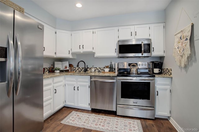 kitchen featuring dark hardwood / wood-style floors, white cabinetry, sink, light stone counters, and stainless steel appliances