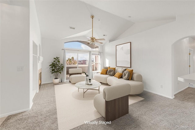 carpeted living room with ceiling fan and vaulted ceiling