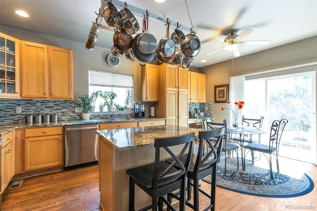 kitchen featuring dishwasher, ceiling fan, light stone counters, and decorative backsplash