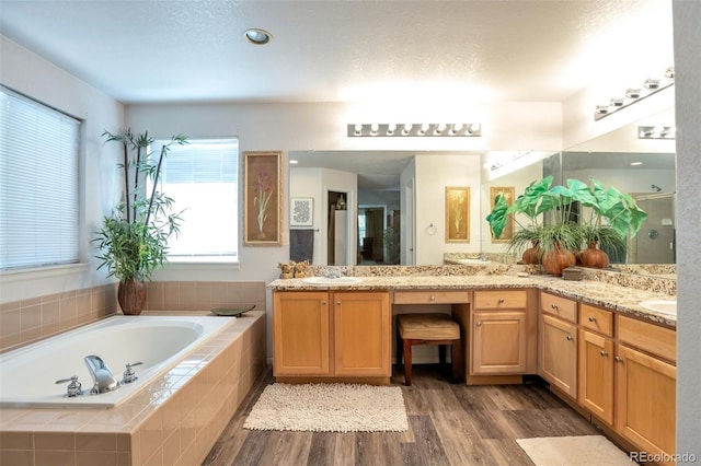 bathroom featuring tiled bath, hardwood / wood-style floors, and vanity