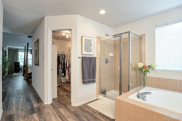 bathroom featuring ceiling fan, wood-type flooring, and shower with separate bathtub