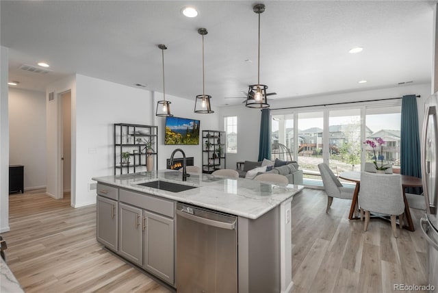 kitchen featuring sink, gray cabinets, hanging light fixtures, an island with sink, and stainless steel dishwasher