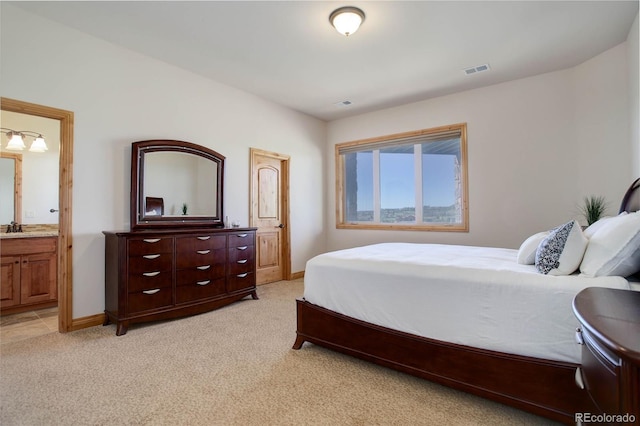 carpeted bedroom with ensuite bath and sink