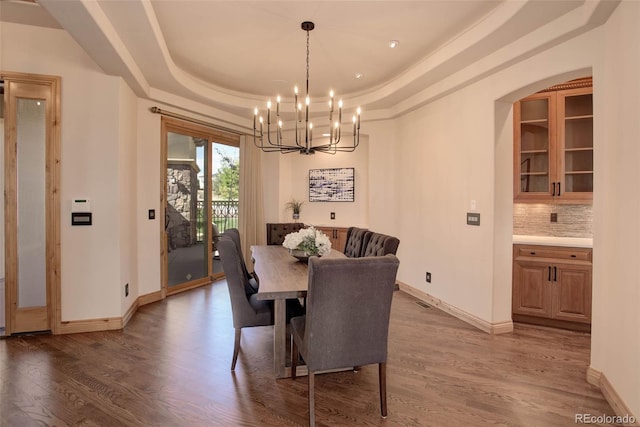 dining area with a tray ceiling, hardwood / wood-style floors, and a chandelier