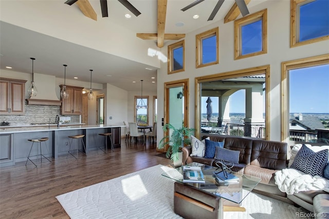 living room featuring dark wood-type flooring, beamed ceiling, a healthy amount of sunlight, and a high ceiling