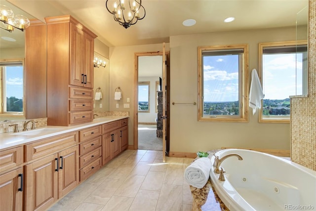 bathroom featuring a notable chandelier, vanity, a bath, and a wealth of natural light