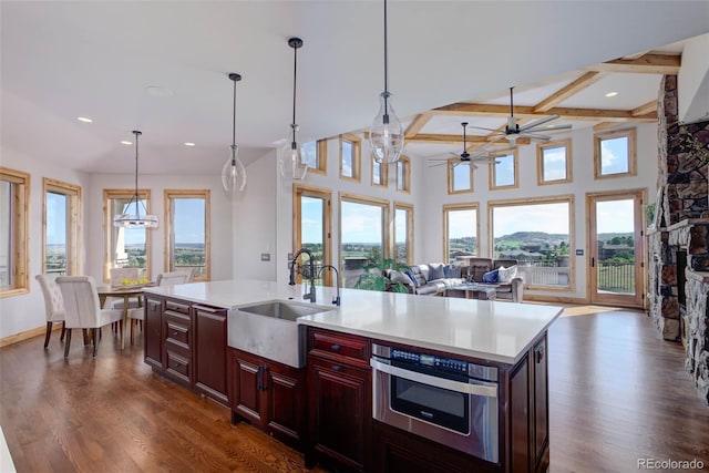 kitchen with dark hardwood / wood-style flooring, decorative light fixtures, plenty of natural light, and a center island with sink