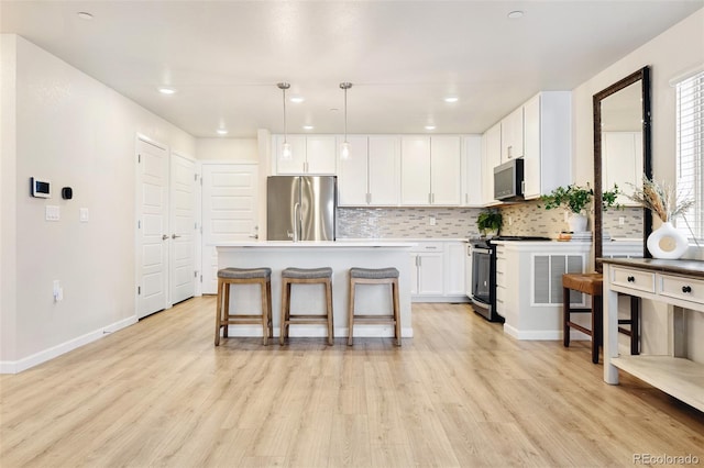 320 Marshall Mews, Superior, CO 80027 - kitchen featuring stainless steel appliances, decorative backsplash, light wood-type flooring, a breakfast bar area, and white cabinets