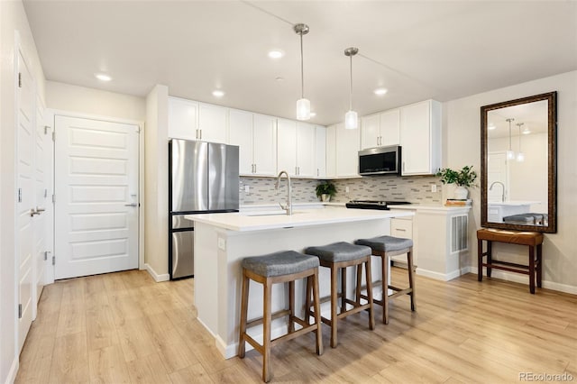 320 Marshall Mews, Superior, CO 80027 - kitchen with appliances with stainless steel finishes, a sink, light wood finished floors, a breakfast bar area, and tasteful backsplash